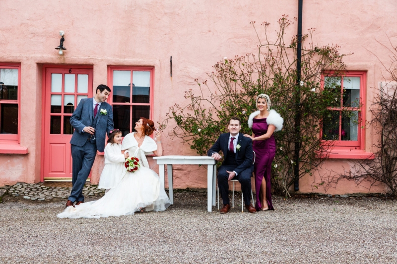Bridal party including flower girl in front of pink pub