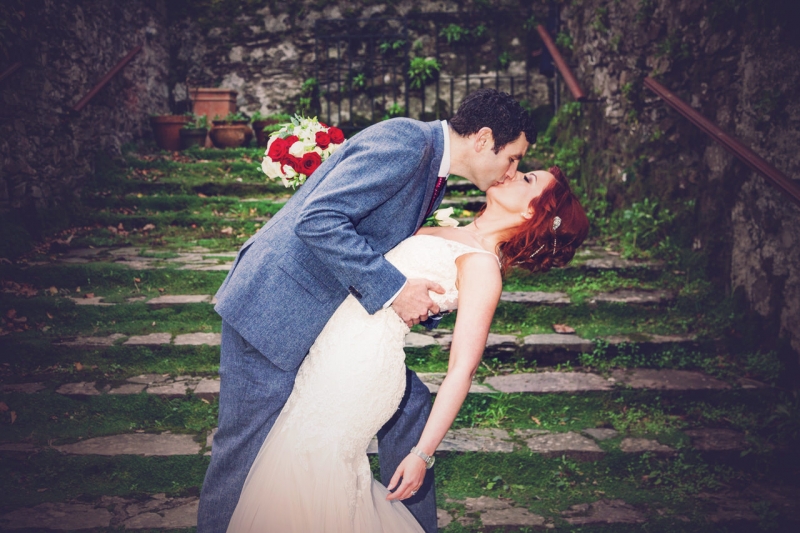Groom dips his bride for a kiss on a moss covered staircase