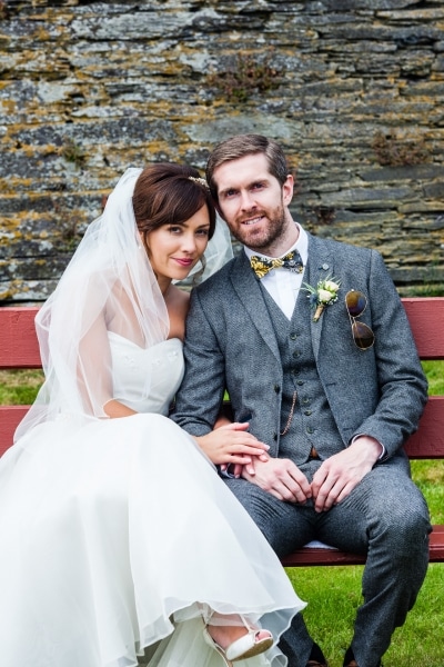 Bride and groom sitting on a red bench in Ring, Clonakilty