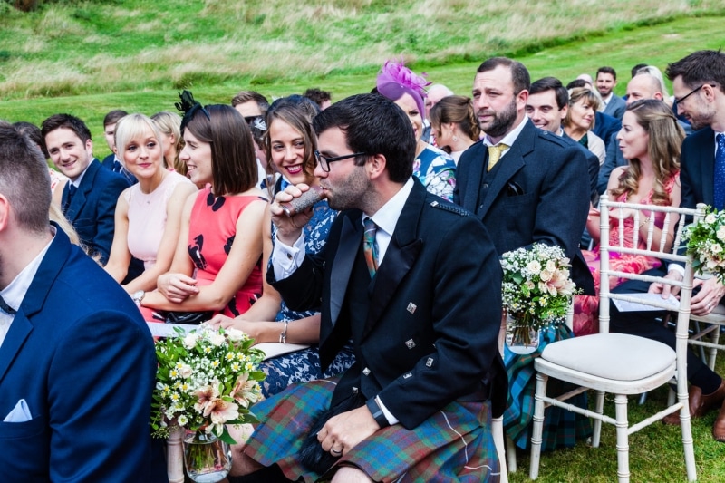 man seated outside sipping from his hip flask waiting for the wedding to start at Fernhill House Hotel