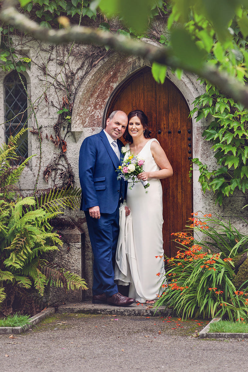 Bride and groom pose in front of door to Honan chapel doo