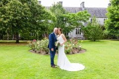 Bride and groom pose in garden at UCC