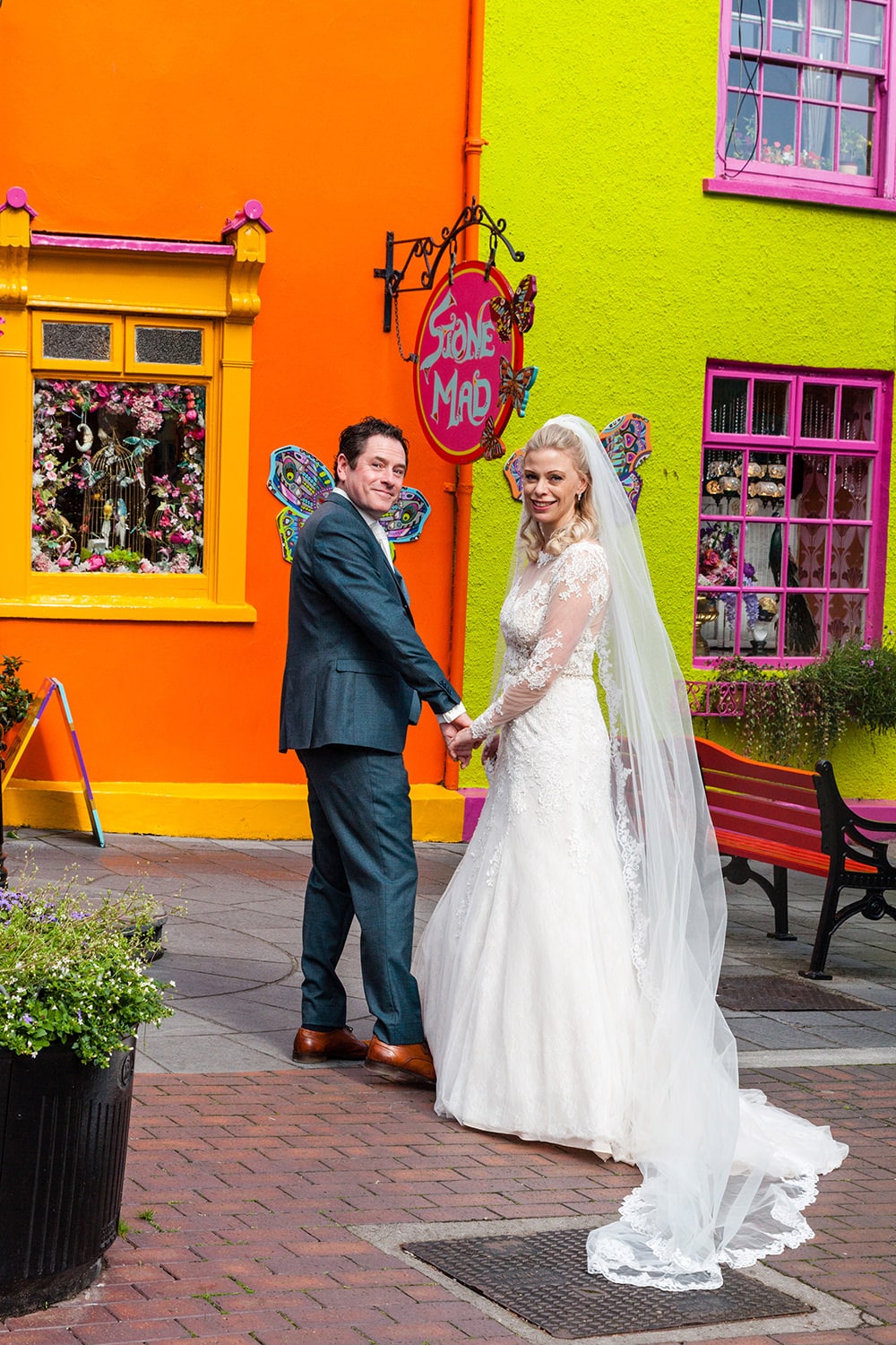 Bride and groom posing in front of colourful Kinsale shopfront