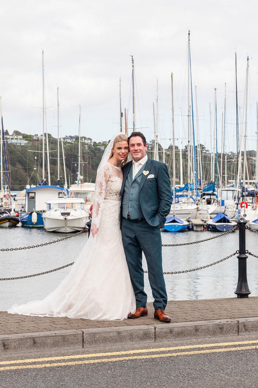 Bride and groom posing by sailboat in kinsale marina