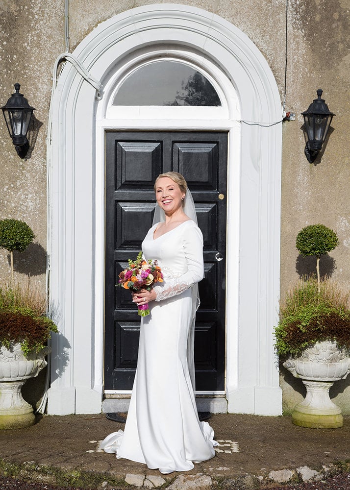 Bride posing with her bouquet in front of a black door