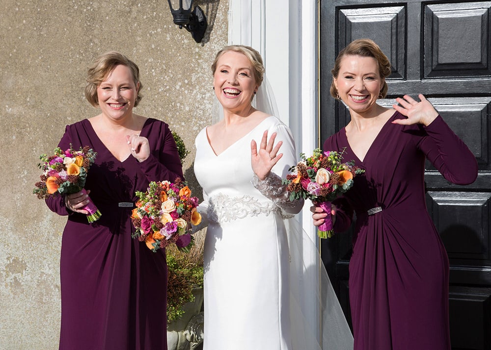 Bride and her bridesmaids in deep reed  pose with their bouquets