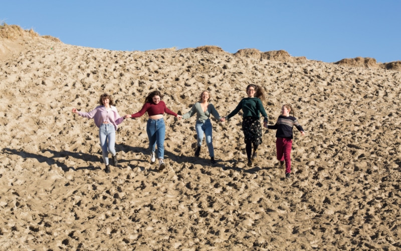 family of mum and four daughters run down a sand dune at Inchydoneybeach